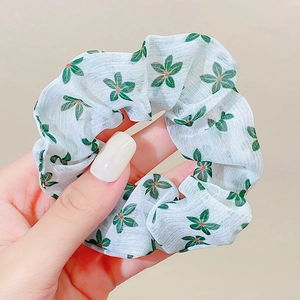 Detail of white organza scrunchie with green leaves and red berries floral pattern