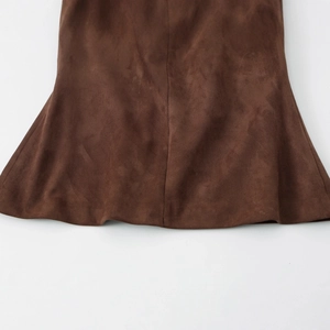 Gros plan de l'ourlet en daim marron montrant la texture des fibres et le drapé ondulé