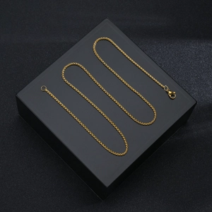 Macro detail of a 2mm gold-plated stainless steel square pearl chain with metallic luster