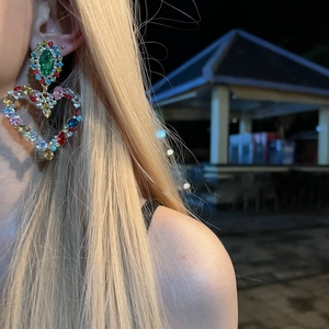 Detailed view of oversized heart earrings with colorful rhinestones on female model