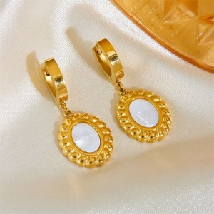 Macro detail of vintage gold oval earrings with white shell inlay on silk fabric