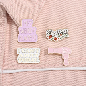 Detailed view of four colorful enamel lapel pins with unique slogans on pink denim fabric