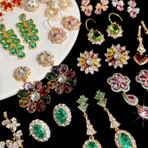 Détail de boucles d'oreilles fleur en zircon coloré et bagues plaquées or