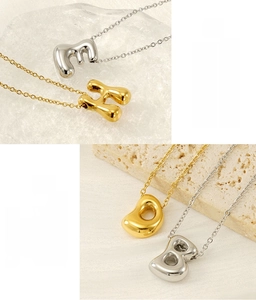 Detailed view of polished 18K gold and silver 26 bubble letter pendants on fine chains