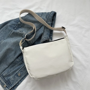 Minimalist white nylon shoulder bag displayed on a denim jacket background
