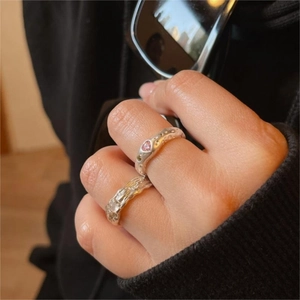 Detail showing two 925 silver rings with a pink heart stone and irregular texture
