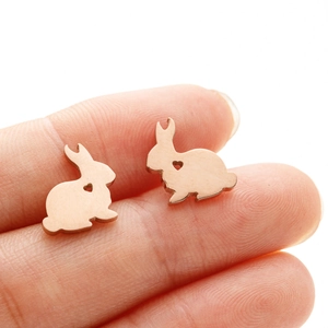 Detail of rose gold bunny earrings with heart cutout held between fingers
