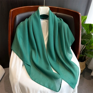 Detail of lightweight green linen scarf draped on white top showing soft texture
