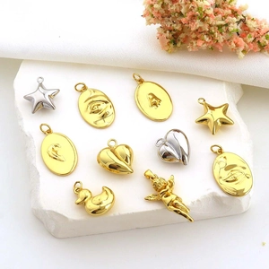 Assorted gold and silver metal charms with star, heart, face, and angel shapes on white stone