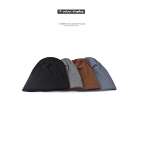 Flat lay of knit beanies in black, dark gray, brown, and blue-grey showing fabric texture
