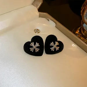 Elegant black flocked heart stud earrings with silver cross motif in a beige jewelry box