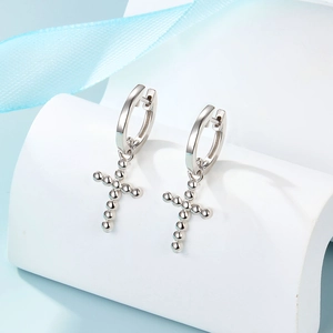 Macro detail of 925 sterling silver hoop earrings with beaded cross charm on display