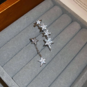 Detailed view of silver star and moon tassel earrings set with cubic zirconia in a jewelry box