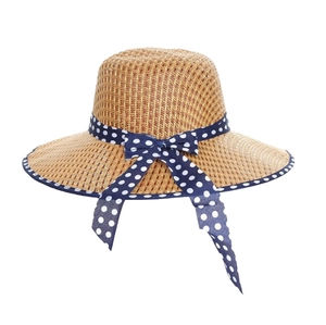 Flat lay of a woven straw sun hat with a navy blue polka dot bow on a white background