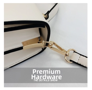 Detail of white leather shoulder bag featuring gold-tone hardware hooks and black edges