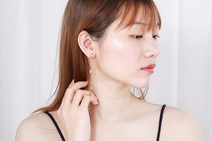 Close-up of elegant gold tassel earrings with clear crystals on female model