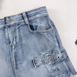 Close-up of high-waist light blue denim shorts with metallic buttons and distressed edges