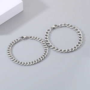 Detail view of two silver stainless steel Cuban link bracelets with lobster clasps
