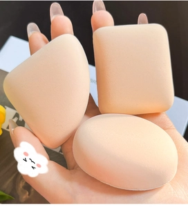 Close-up of three beige makeup sponges in teardrop, square, and oval shapes on a hand