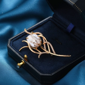 Elegant gold coral brooch with baroque pearl and cubic zirconia in a blue jewelry box