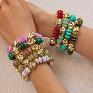 Close-up of stacked acrylic beaded bracelets with irregular gold metal accents for women