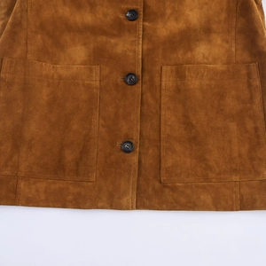 Détail de la veste en daim marron montrant la texture, les boutons et les poches