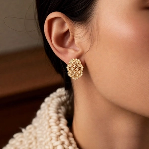 Close-up of model wearing gold hollow flower earrings with vintage palace style and fine details