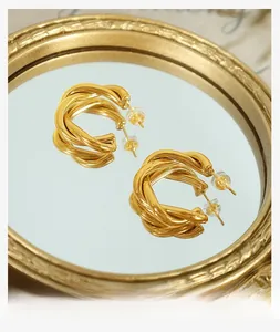 Macro shot of gold twisted rope hoop earrings with metal reflection on a round mirror