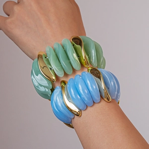 Detail of acrylic stretch bracelet showing blue and green marbled textures with gold metal