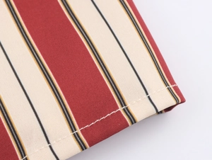 Gros plan sur un tissu rayé rouge et beige avec des coutures blanches et texture