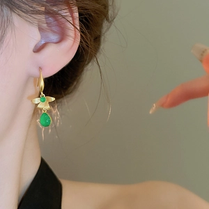 Vintage gold brushed metal earrings with green resin teardrop pendant on model