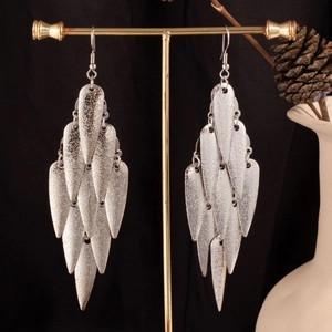 Detailed close-up of tiered silver leaf-shaped tassel earrings on a gold display stand