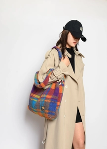 Detail of the colorful plaid plush tote bag showing the textured faux fur and brand tag