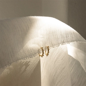 Classic 14K gold-plated hoop earrings with beaded texture on white fabric backdrop