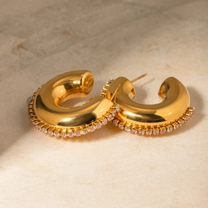 Macro view of 18k gold C-shaped earrings with pink and clear rhinestone inlay details