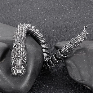 Detail of vintage dragon link bracelet in steel with green eyes and carved scales