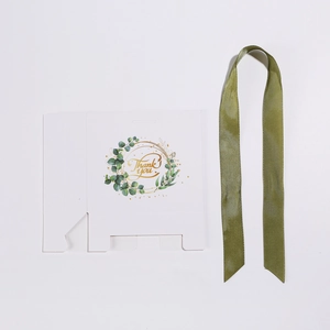Detailed view of white wedding gift box with eucalyptus wreath and green satin ribbon