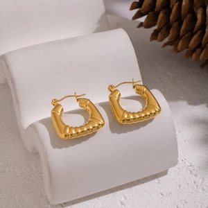 Créoles texturées en forme de U plaquées or 18 carats sur un support ondulé blanc élégant