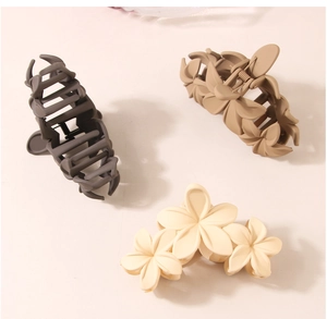 Close-up of matte floral and geometric hair claws in grey, beige, and cream colors