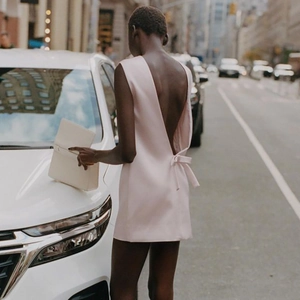 Detalle de vestido mini rosa sin espalda con un lazo decorativo grande en la parte baja