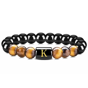 Détail macro du bracelet en onyx et œil de tigre avec perle rectangulaire lettre K dorée