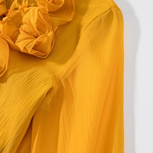 Detailed shot of yellow chiffon fabric featuring intricate ruffled collar and pleat textures