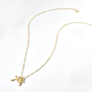 Macro shot of gold layered necklace featuring triple cross pendants and fine O-chain link