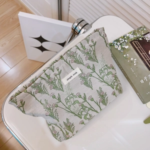 Green floral cotton makeup bag with Simple Wish label on white desk setup