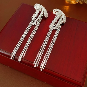 Detail of silver tassel earrings with sparkling rhinestones on a vintage jewelry box