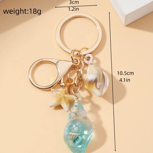 Detailed size and weight view of golden keychain with shell, starfish and conch charms