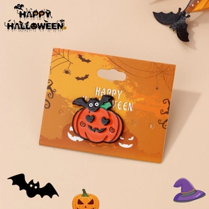 Close-up of enamel pumpkin and bat pin displayed on a festive Halloween card