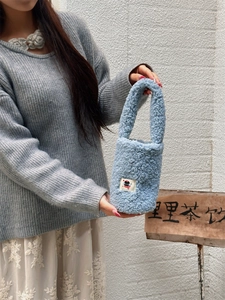 Close-up of light blue plush carrier bag with cartoon patch for tumblers and cups
