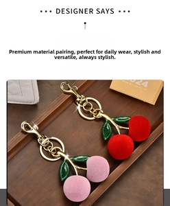 Detailed view of red and pink flocking cherry keychains with polished gold hardware