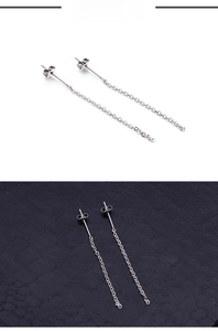 Detailed view of silver stainless steel chain tassel earrings on a textured surface